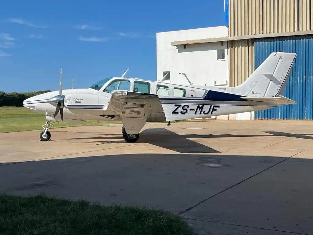 KZN Aviation's Baron 58 aircraft ZS-MJF parked at hangar, featuring twin piston engines and 1500km range for luxury air travel.